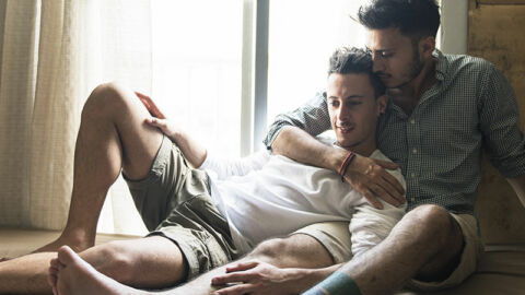 two guys laying in bed affectionately