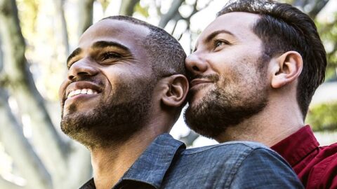 mixed race gay couple enjoying a hug outside